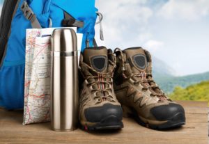 hiking boots, map, water bottle, and bag sitting on a hill