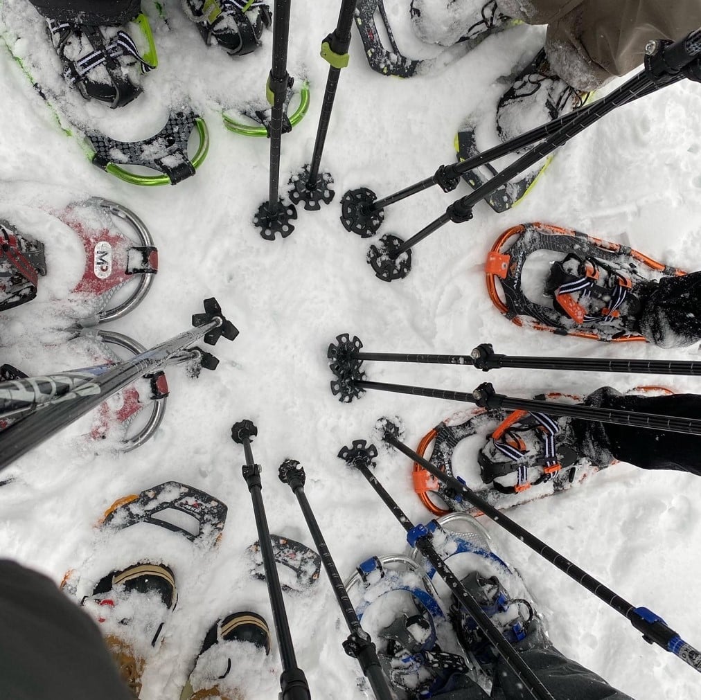People with snowshoes standing in a circle before heading out.