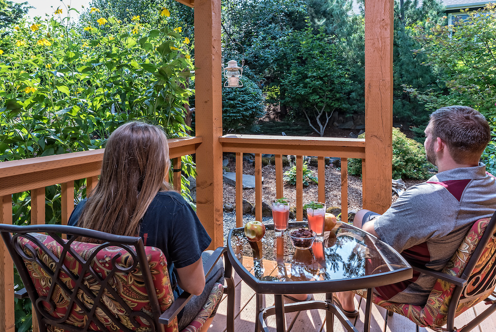 A couple enjoying a drink on the porch of our luxury cabins in the Columbia River Gorge - a great place for romantic getaways in Washington State
