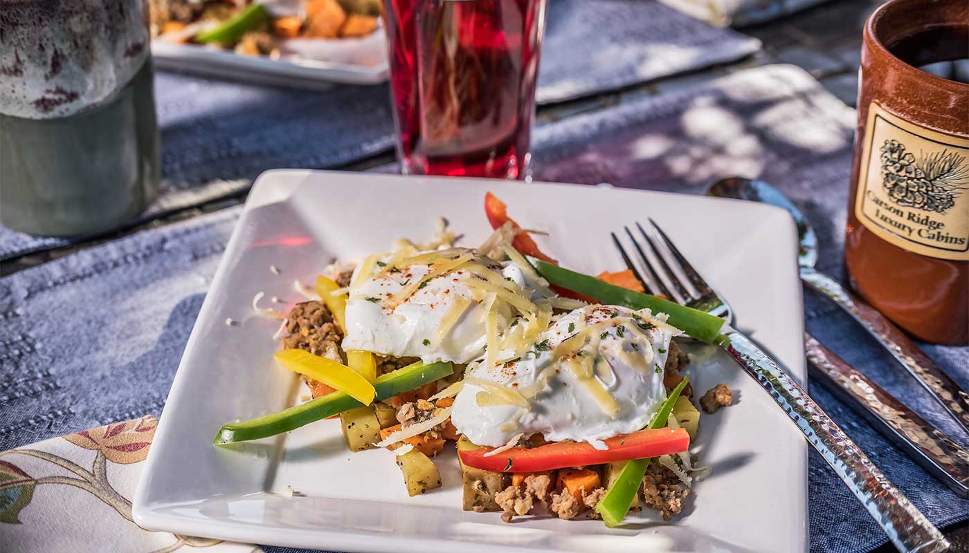 A plate of sweet potato hash with eggs on a bistro table for breakfast at Carson Ridge Luxury Cabins in Washington State.