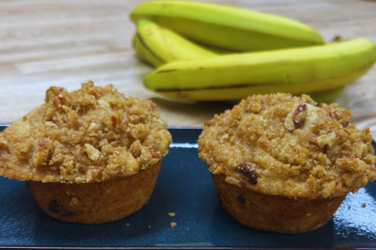 Two Banana Nut Crumb Muffins hot out of the oven, cool on a plate before serving for breakfast at Carson Ridge Luxury Cabins in Washington State. Read on to make this muffin recipe in your home.