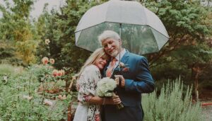 A middle age couple under an umbrella during their romantic elopement in Washington State at our Columbia River Gorge Cabins